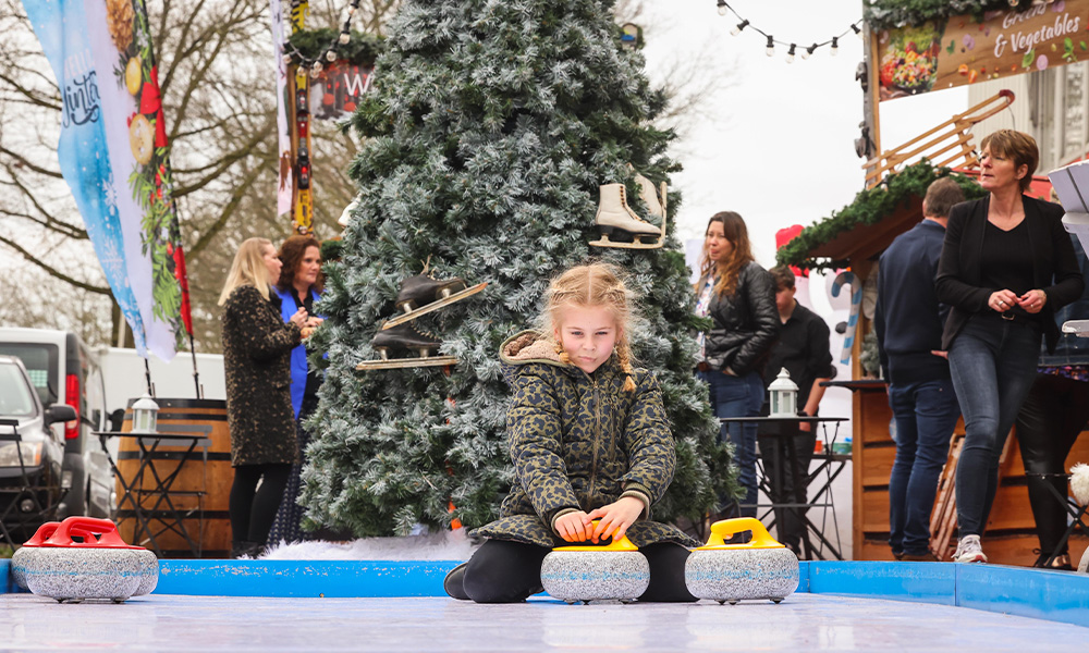 Bezoekers spelen curling op een winterevent